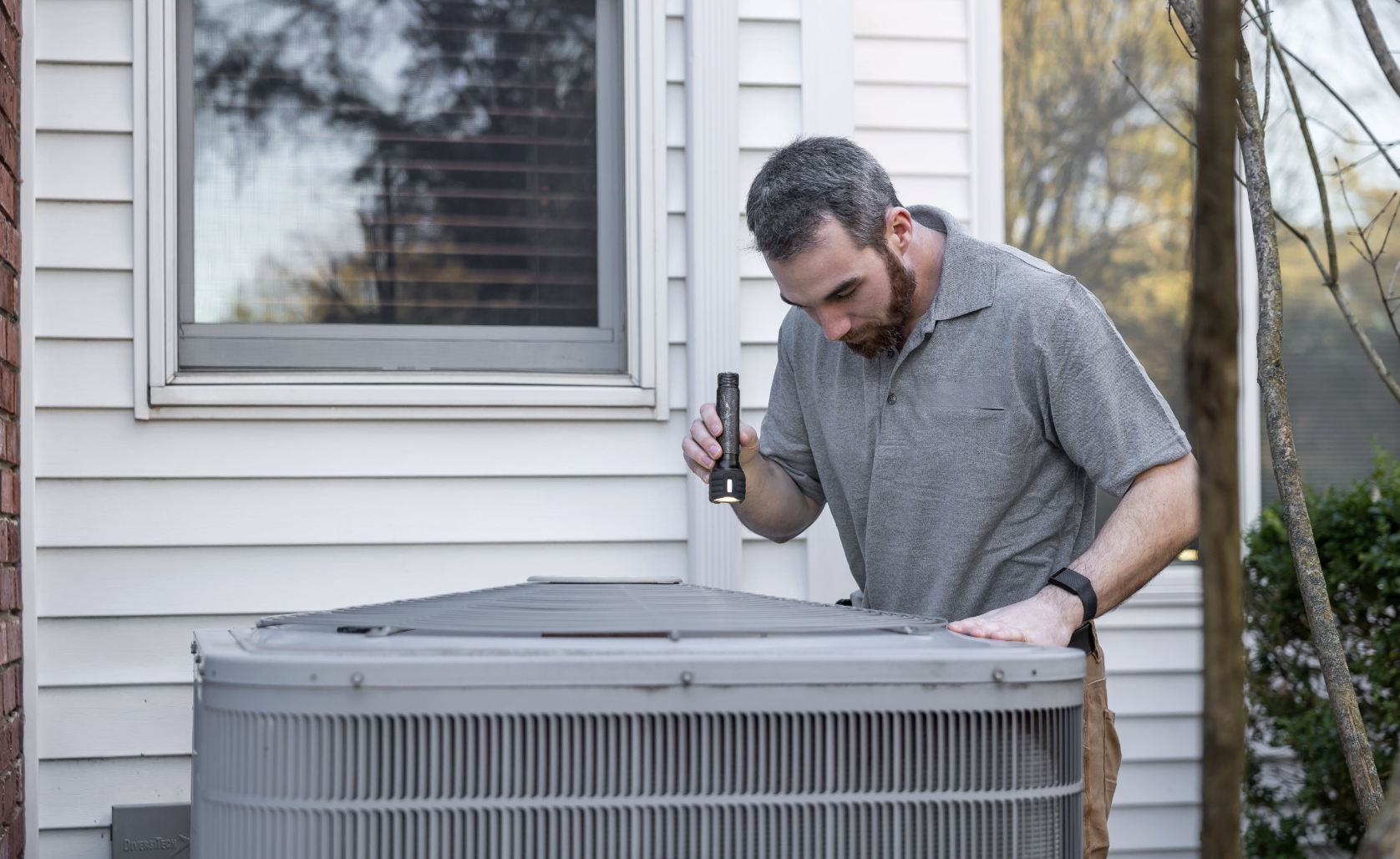 HVAC technician inspecting an outdoor air conditioning unit
